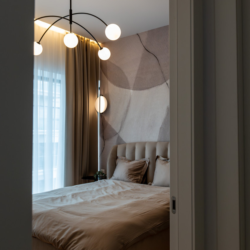 Tapet modern cu design minimalist, Asana, Sand, cu o pat în cameră, un perete gri cu modele abstracte, o oglindă pe un perete și un ghiveci cu ananas lângă fereastră