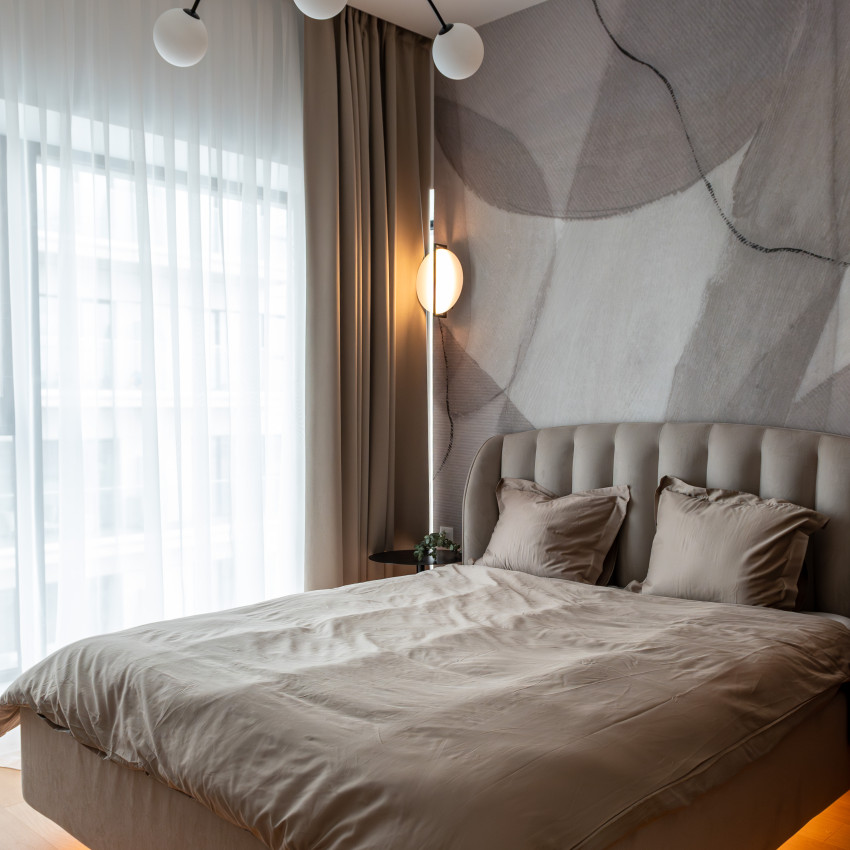 Tapet modern cu design minimalist, Asana, Sand, cu o pat în cameră, un perete gri cu modele abstracte, o oglindă pe un perete și un ghiveci cu ananas lângă fereastră
