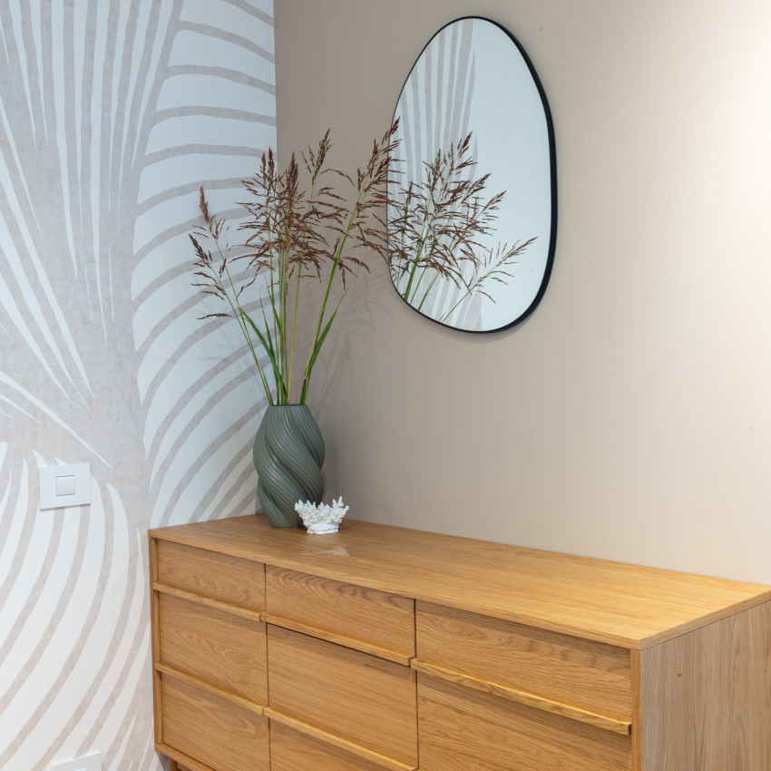 Tapet cu model abstract de linii curbe, în nuanțe de nisipiu și alb, aplicat pe peretele unui living modern, cu canapea și fotoliu asortate.