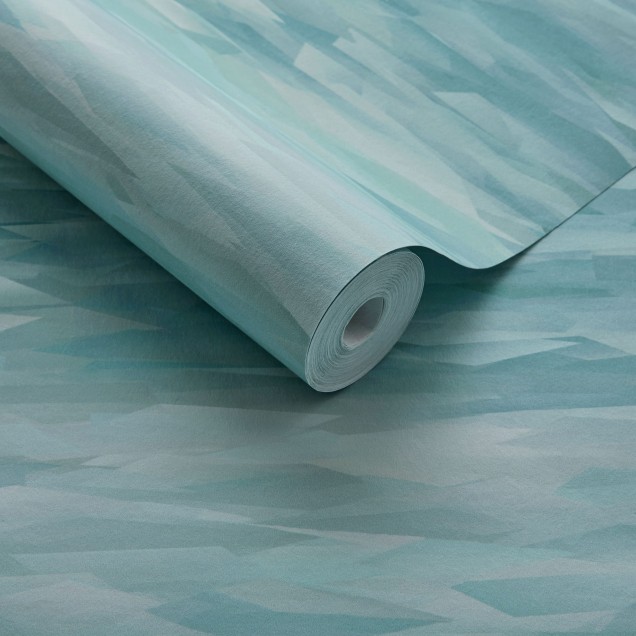 Tapet geometric modern cu un design abstract în nuanțe de verde mineral. Tapetul este prezentat pe un perete, cu o canapea, o măsuță de cafea și o lampă în fața sa.