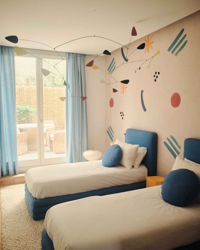 Tapet cu design geometric abstract, cu forme rotunde si linii, in culori pastelate si vibrante, intr-o camera de copii.
