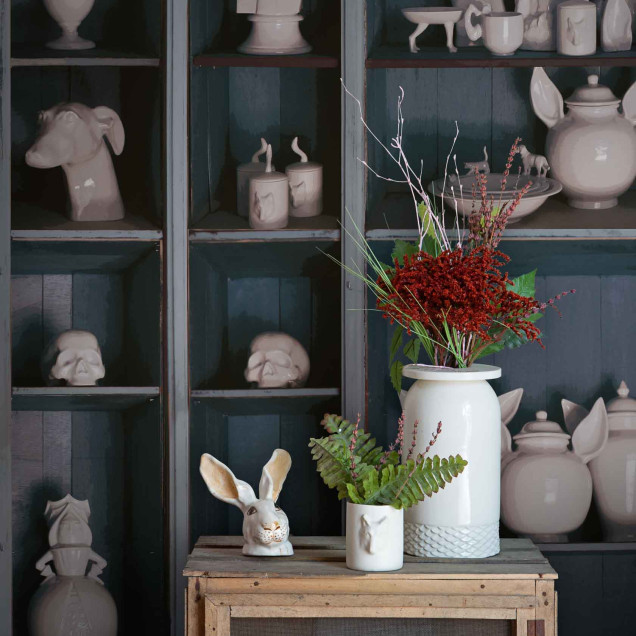 Tapet cu design ceramic faunistic, prezentând diverse obiecte decorative ceramice în formă de animale și figuri, expuse pe rafturi.