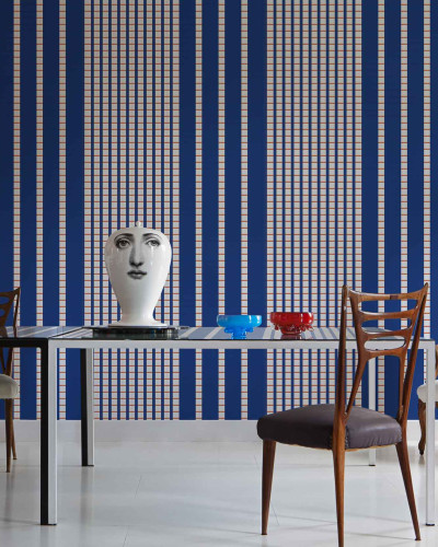 Tapet geometric cu dungi albastre, crem si linii portocalii, asezat pe peretele unei sufragerii moderne.