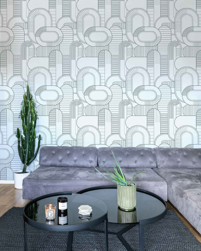Tapet cu model geometric abstract în nuanțe de gri și alb, aplicat pe un perete din spatele unui set de canapele gri și a unei măsuțe de cafea negre.