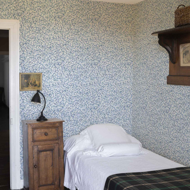 Tapet cu model delicat de frunze albastre pe fundal alb, intr-o camera decorata in stil rustic.