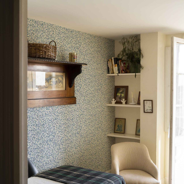 Tapet cu model delicat de frunze albastre pe fundal alb, intr-o camera decorata in stil rustic.