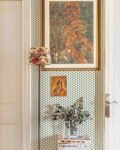 Tapet verde cu model de frunze într-un interior decorat cu tablouri