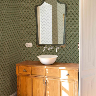 Tapet floral verde smarald într-o baie cu mobilier vintage