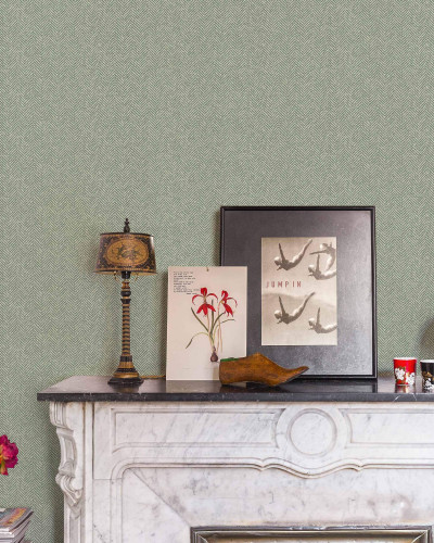 Tapet verde cu model subtil în zig-zag într-o cameră decorată cu șemineu și obiecte decorative vintage.