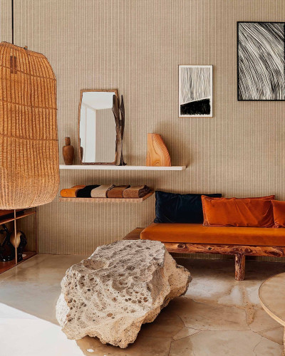 Tapet bej texturat cu dungi subtiri, prezentat intr-un living modern cu mobilier din lemn si accente textile portocalii