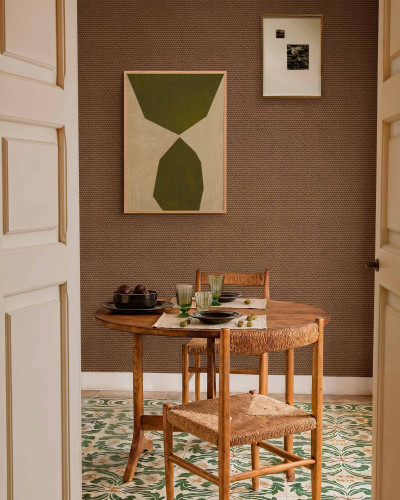 Tapet cu textură de culoarea maro închis, prezentat într-un decor de dining cu masă din lemn și scaune din ratan.