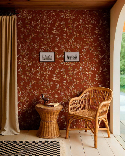 Tapet cu model botanic pe fundal teracota, într-un decor cu mobilier din ratan.