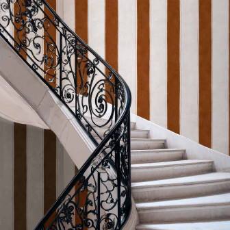 Tapet cu dungi verticale în nuanțe de cafea pe un perete lângă o scară elegantă