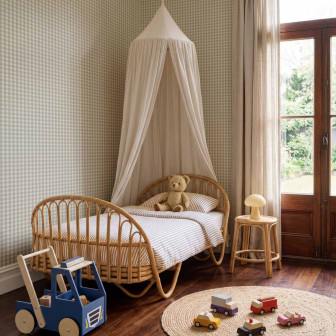 Tapet cu model caro în nuanțe de mint și crem, aplicat pe peretele unei camere de copii cu pat de rattan.
