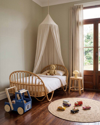Tapet cu model caro în nuanțe de mint și crem, aplicat pe peretele unei camere de copii cu pat de rattan.