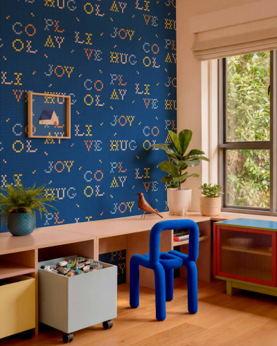 Tapet cu litere colorate in stil pixelat pe fundal albastru indigo intr-o camera de zi moderna.
