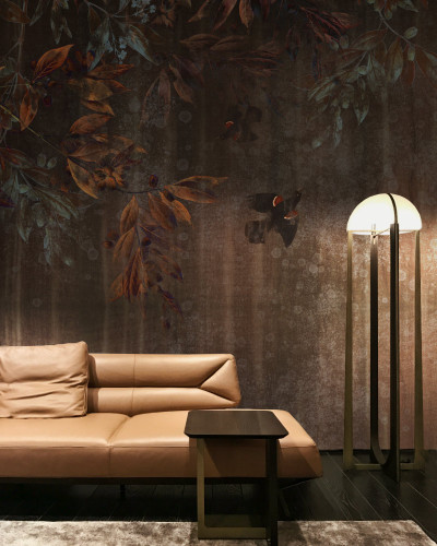 Tapet mural contemporan cu design floral, imagine de fundal maronie, cu textura discretă, pe care sunt imprimate ramuri cu frunze de diverse nuanțe de maro, mov, verde și albastru. Printre ramuri se zăresc pasări negre cu un punct roșu pe aripi.