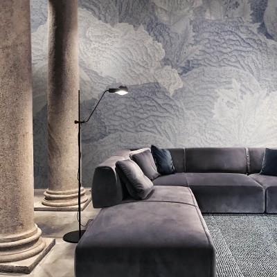 Tapet contemporan cu design abstract, care prezintă frunze în nuanțe delicate de albastru și gri. Tapetul este aplicat pe un perete din spatele unui canapea gri în formă de L.