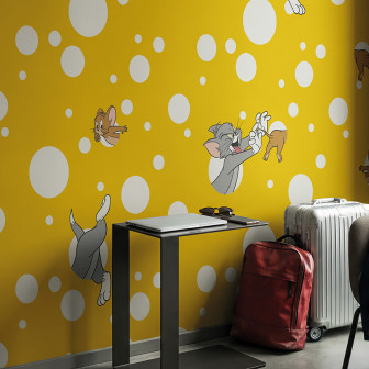 Fototapet Tom și Jerry cu buline albe pe fundal galben vibrant, decorând o cameră modernă cu elemente de voiaj.