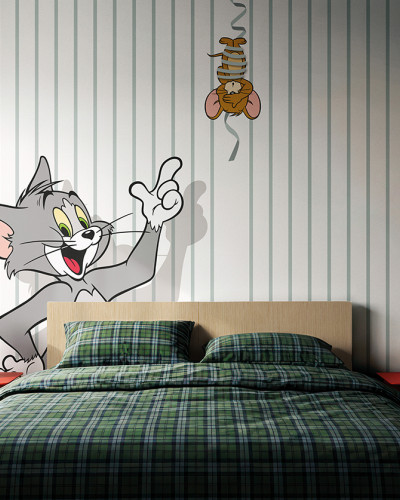Fototapet Tom și Jerry 107 într-o cameră de copii, cu Tom zâmbitor și Jerry suspendat pe o panglică, pe un fundal cu dungi verticale verzi pal și albe. Pat cu așternuturi în carouri verzi, noptiere roșii.