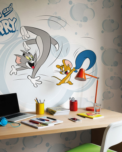 Fototapet Tom and Jerry 108 pe un perete deasupra unui birou de lemn cu un laptop și obiecte de papetărie. Tapetul prezintă pe Tom și Jerry în acțiune, pe un fundal cu nori albastru-gri.