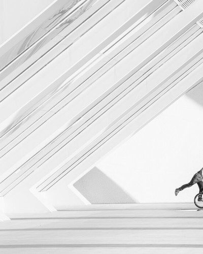 Fototapet cu un ciclist BMX realizând o manevră într-un spațiu modern, alb-negru