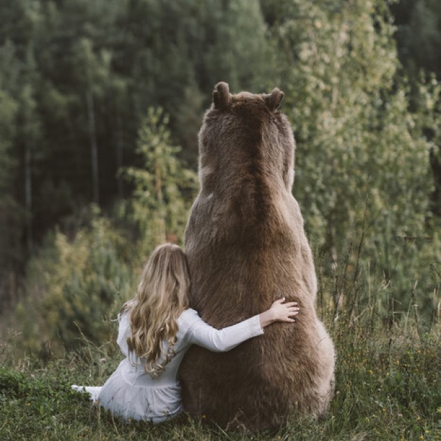 Tapet cu o fată îmbrățișând un urs în pădure.