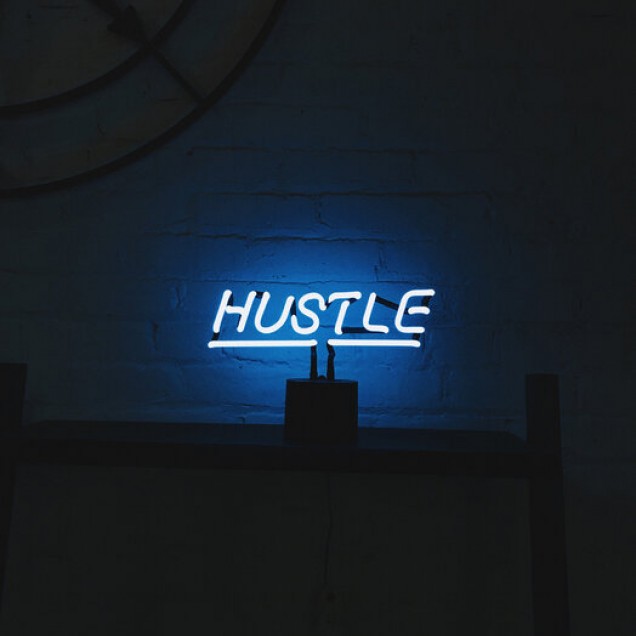Hustle Neon Sign Photowall, tapet cu un semn neon luminos pe un fundal întunecat, ideal pentru a crea o atmosferă modernă și vibrantă.