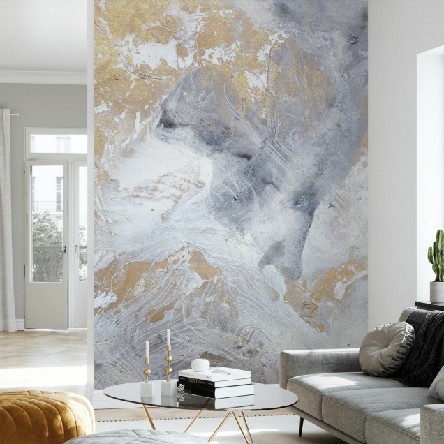 Tapet modern cu design abstract, cu nuanțe de aur și gri, în stil minimalist, decorat pe un perete din dormitor, lângă un pat cu lenjerie gri și o noptieră cu o lampă.