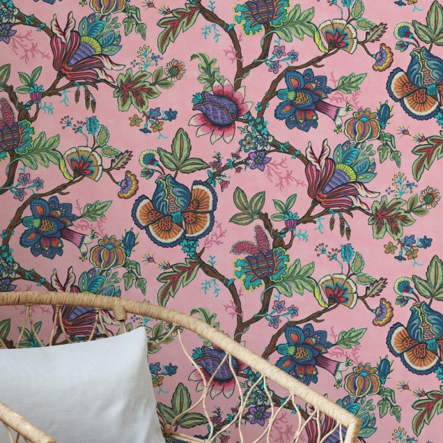 Tapet cu model floral vibrant, in nuante de roz, cu flori colorate si frunze verzi, decorat cu un canapea bleumarin, o masuta de cafea si o planta in ghiveci.