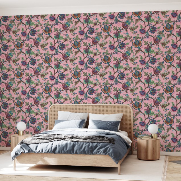 Tapet cu model floral vibrant, in nuante de roz, cu flori colorate si frunze verzi, decorat cu un canapea bleumarin, o masuta de cafea si o planta in ghiveci.