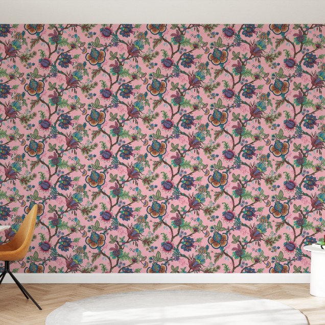 Tapet cu model floral vibrant, in nuante de roz, cu flori colorate si frunze verzi, decorat cu un canapea bleumarin, o masuta de cafea si o planta in ghiveci.
