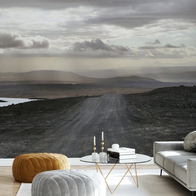A wallpaper with a scenic view of a winding road in a desolate landscape under a cloudy sky.