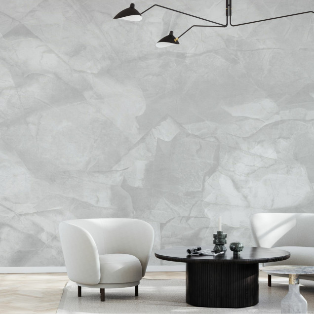 Tapet cu aspect de beton gri deschis, decorat cu un candelabru, o canapea gri si o masuta cu o cana de ceai pe ea.