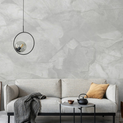 Tapet cu aspect de beton gri deschis, decorat cu un candelabru, o canapea gri si o masuta cu o cana de ceai pe ea.