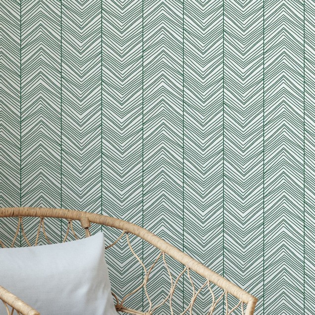 Tapet Herringbone Green în living, cu canapea gri și scaun din răchită.