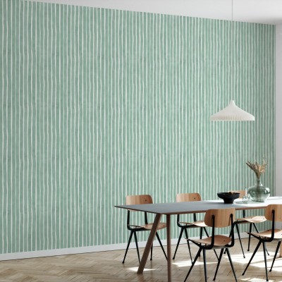 Tapet decorativ cu dungi verticale in acuarela, in nuante de verde, aplicat intr-un living cu o masa si scaune din lemn, langa o canapea alba.