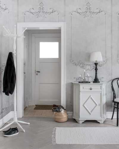 Tapet 3D cu un design clasic, 3D Noble Flair,  care prezintă un model detaliat în relief, cu nuanțe de gri.  Tapetul este prezentat într-un hol, pe un perete cu  o ușă albă și  un mobilier elegant.