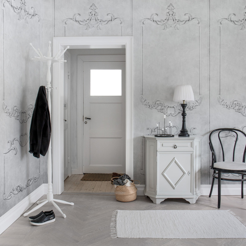 Tapet 3D cu un design clasic, 3D Noble Flair,  care prezintă un model detaliat în relief, cu nuanțe de gri.  Tapetul este prezentat într-un hol, pe un perete cu  o ușă albă și  un mobilier elegant.