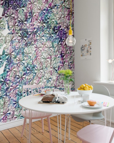 Tapet cu model geometric, Florigami, în culori vibrante, decorând un perete într-o cameră de luat masa.