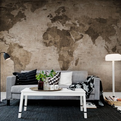 Harta lumii vintage maro pe peretele din spatele unei canapele, decorata cu perne si o patura