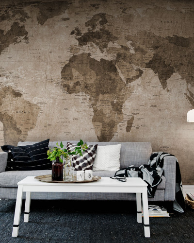 Harta lumii vintage maro pe peretele din spatele unei canapele, decorata cu perne si o patura