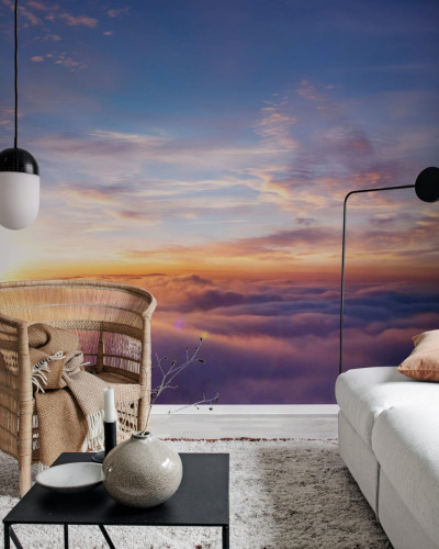 Un tapet cu un apus de soare vibrant, reflectat în nori, într-un living modern.
