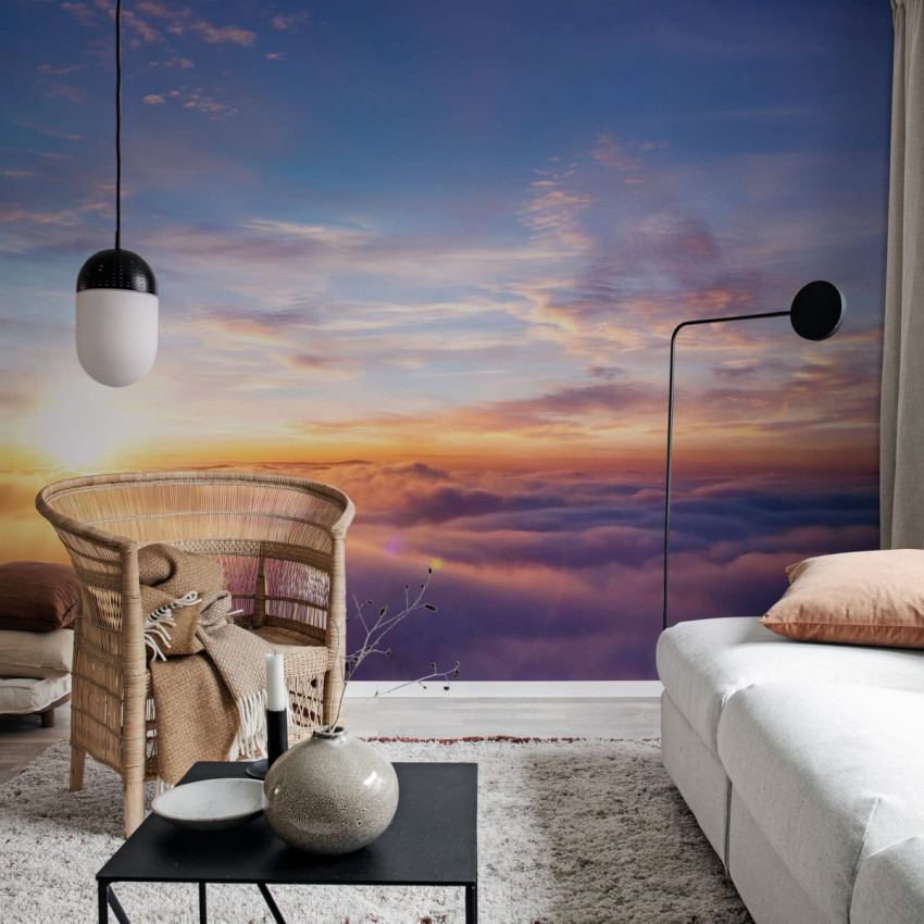 Un tapet cu un apus de soare vibrant, reflectat în nori, într-un living modern.