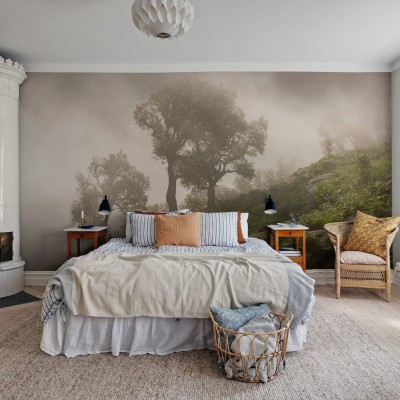 Un tapet cu un design realist al unui deal împădurit învăluit în ceață. Tapetul este aplicat pe un perete într-un dormitor, creând o atmosferă relaxantă și invitantă.