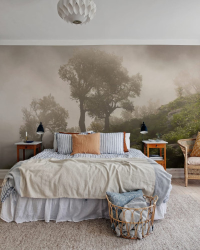 Un tapet cu un design realist al unui deal împădurit învăluit în ceață. Tapetul este aplicat pe un perete într-un dormitor, creând o atmosferă relaxantă și invitantă.