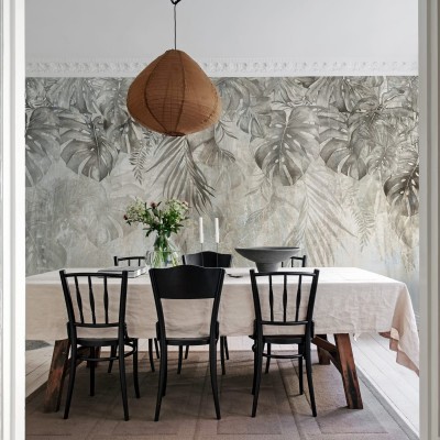 Tapet cu frunze de Monstera într-un interior modern, decorat cu o masă din lemn și scaune negre.