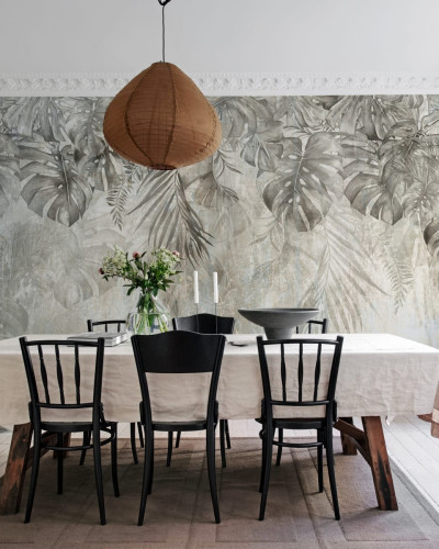 Tapet cu frunze de Monstera într-un interior modern, decorat cu o masă din lemn și scaune negre.