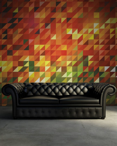 Tapet geometric abstract Slanted cu culori calde,  pe un perete din spatele unei canapele negre
