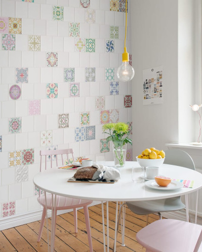 Wallpaper cu model geometric vintage, cu accente de culoare vibrante, decorand o bucatarie moderna cu masa si scaune roz